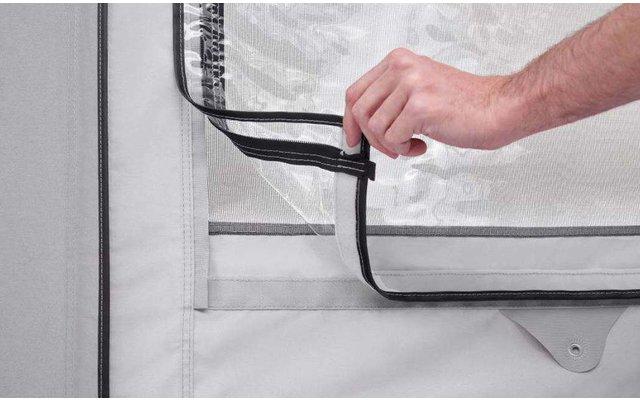 Main tenant une fermeture éclair noire sur un tissu de tente blanc