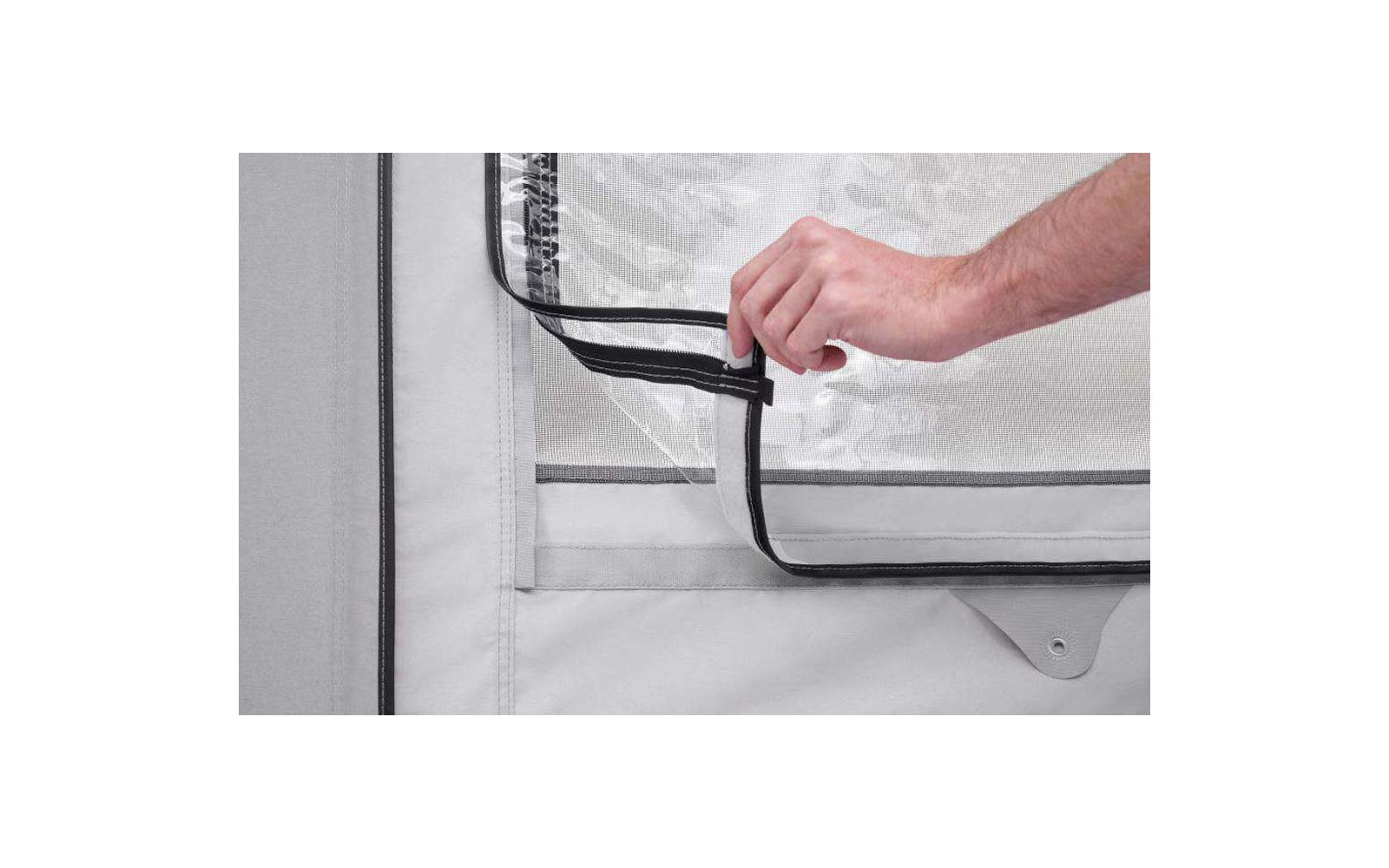 Main tenant une fermeture éclair noire sur un tissu de tente blanc
