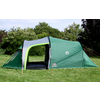 Groene tent met open ingang op een grasveld, omgeven door bomen