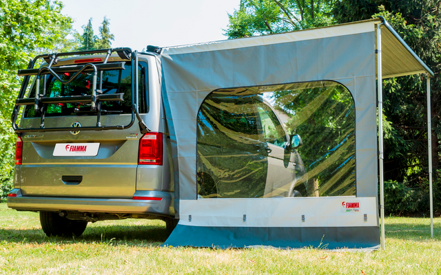 Camper parcheggiato con tenda annessa su un prato