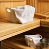 Weiße Handtücher liegen gefaltet auf einer Holzbänken in einer Sauna