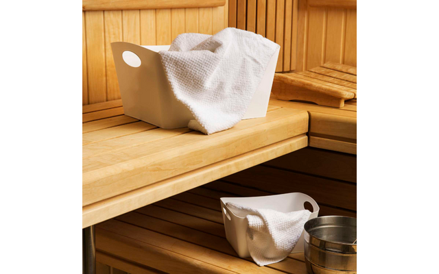 Weiße Handtücher liegen gefaltet auf einer Holzbänken in einer Sauna