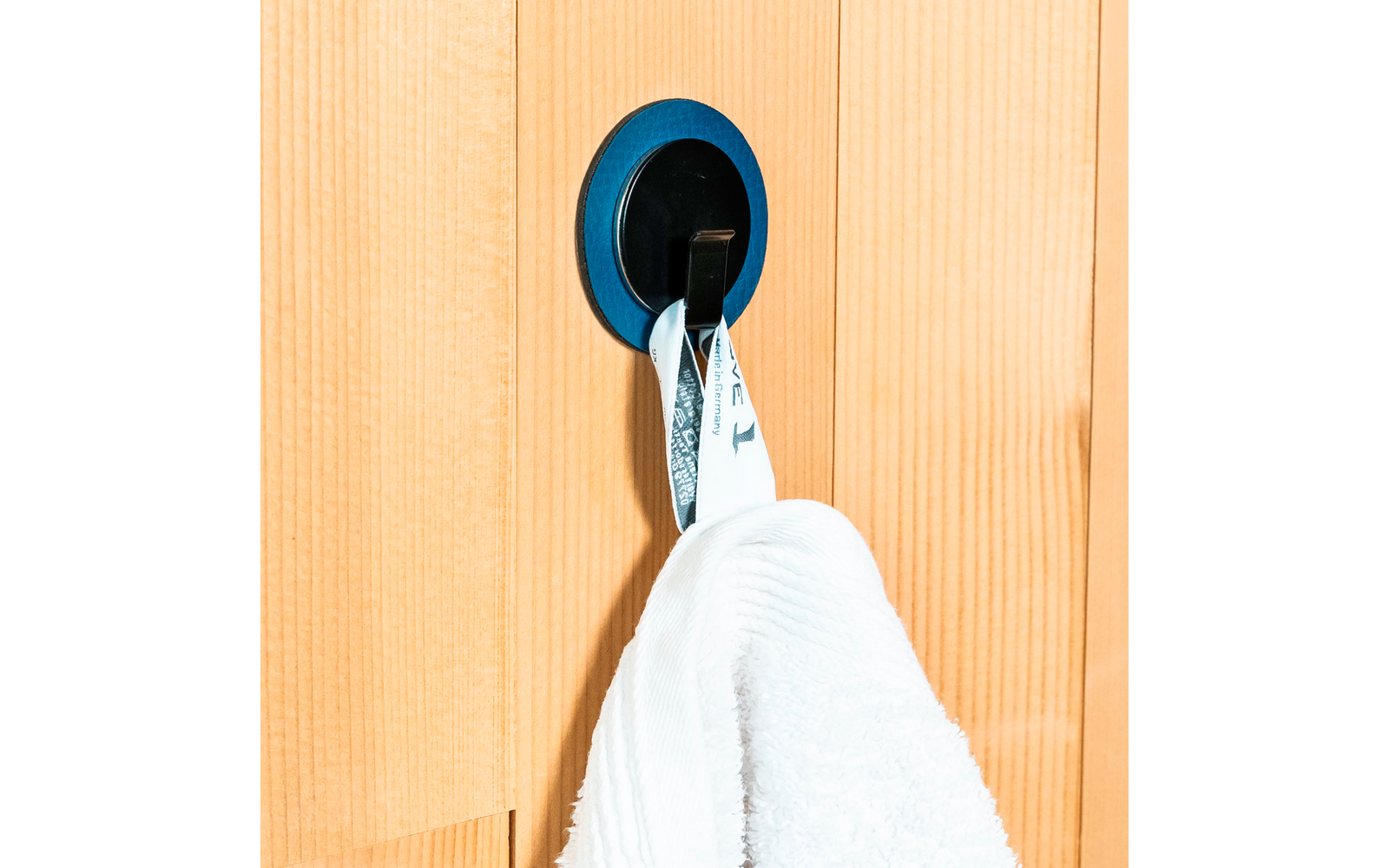 Serviette blanche suspendue à un crochet noir sur une porte en bois