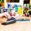 A hand pressing a bell on a wooden table with drinks and a menu