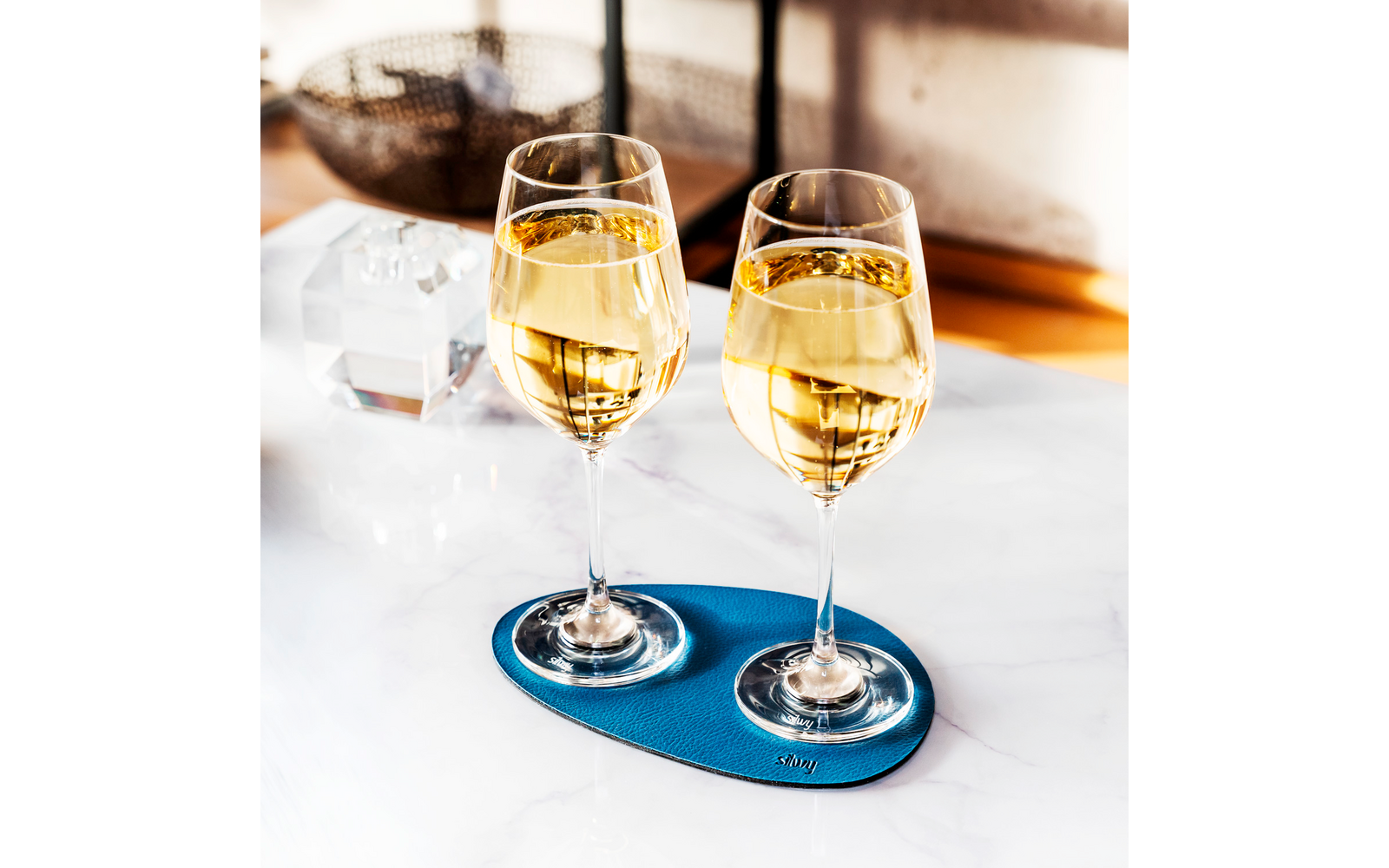 Two glasses of white wine on a blue coaster