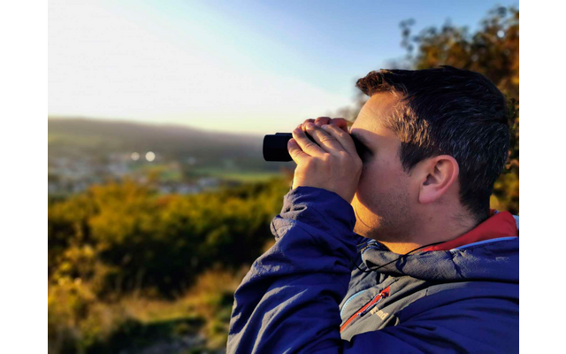 Hombre mirando a través de prismáticos en la naturaleza