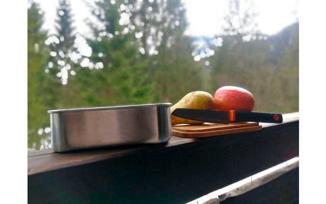 Blikken en fruit op een balkonleuning met bos en bergen op de achtergrond