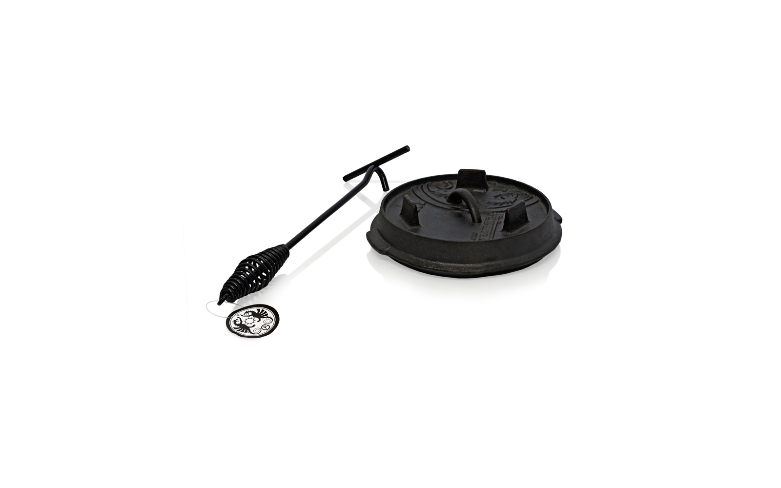 Een zwarte gietijzeren grillpan met deksel en een grilllifters met een lange steel
