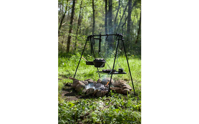 Parrilla sobre fuego abierto en un bosque con árboles verdes de fondo