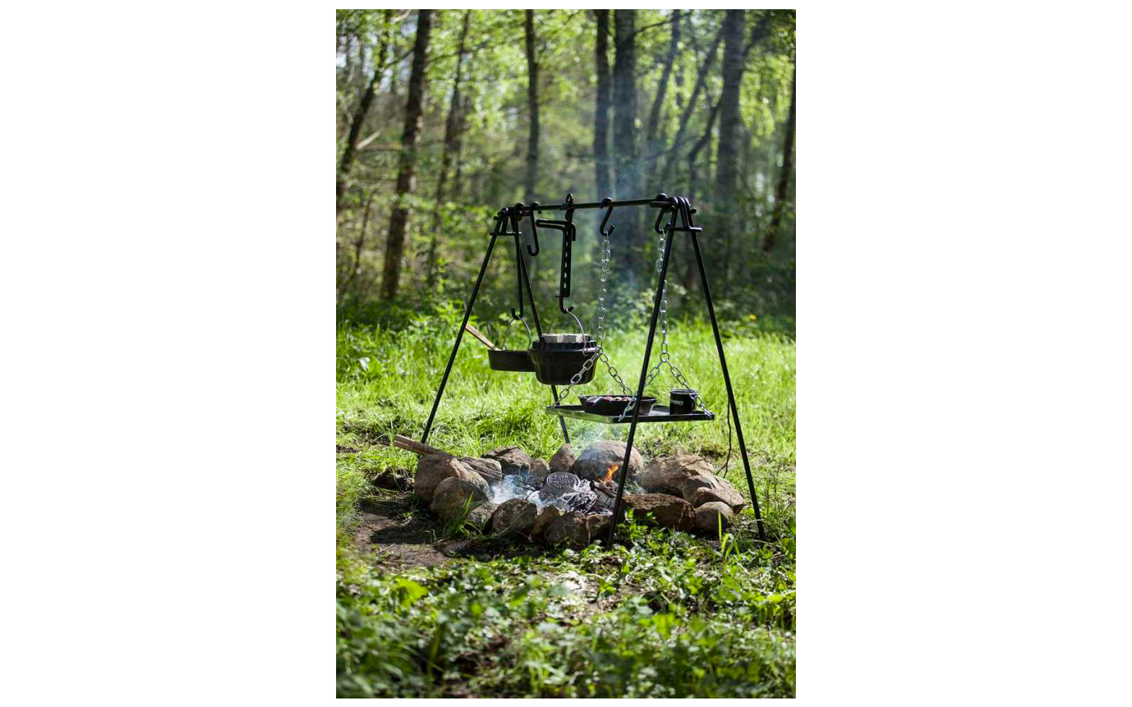 Parrilla sobre fuego abierto en un bosque con árboles verdes de fondo