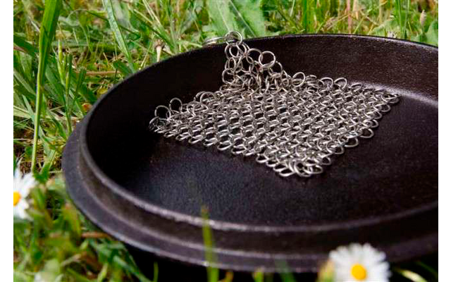 Ein quadratisches Kettenhemd aus Metall liegt auf einer schwarzen Schale im Gras