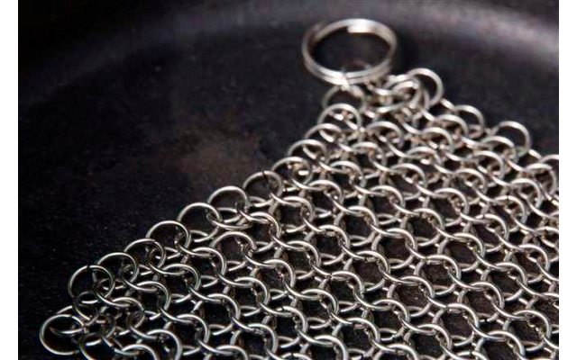 Nahaufnahme eines Kettenhemd-Abschnitts aus Metallringen auf einer schwarzen Oberfläche