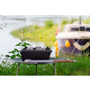 Parrilla sobre una mesa en el jardín, con un barco y plantas verdes al fondo