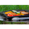 Una parrilla con varias verduras y un trozo de carne, césped de fondo