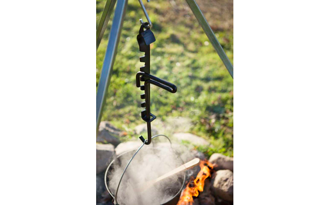 Ein schwarzer Angelrutenhalter mit Haken hängt über einem Lagerfeuer im Freien