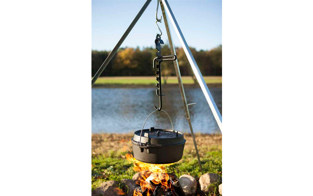 Ein schwarzer Kochtopf hängt an einem Metallgestell über einem Lagerfeuer am See