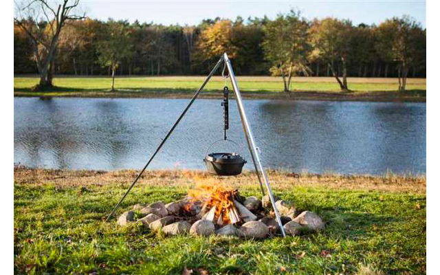 Freiluftfeuerstelle mit kochendem Topf über dem Feuer und See im Hintergrund