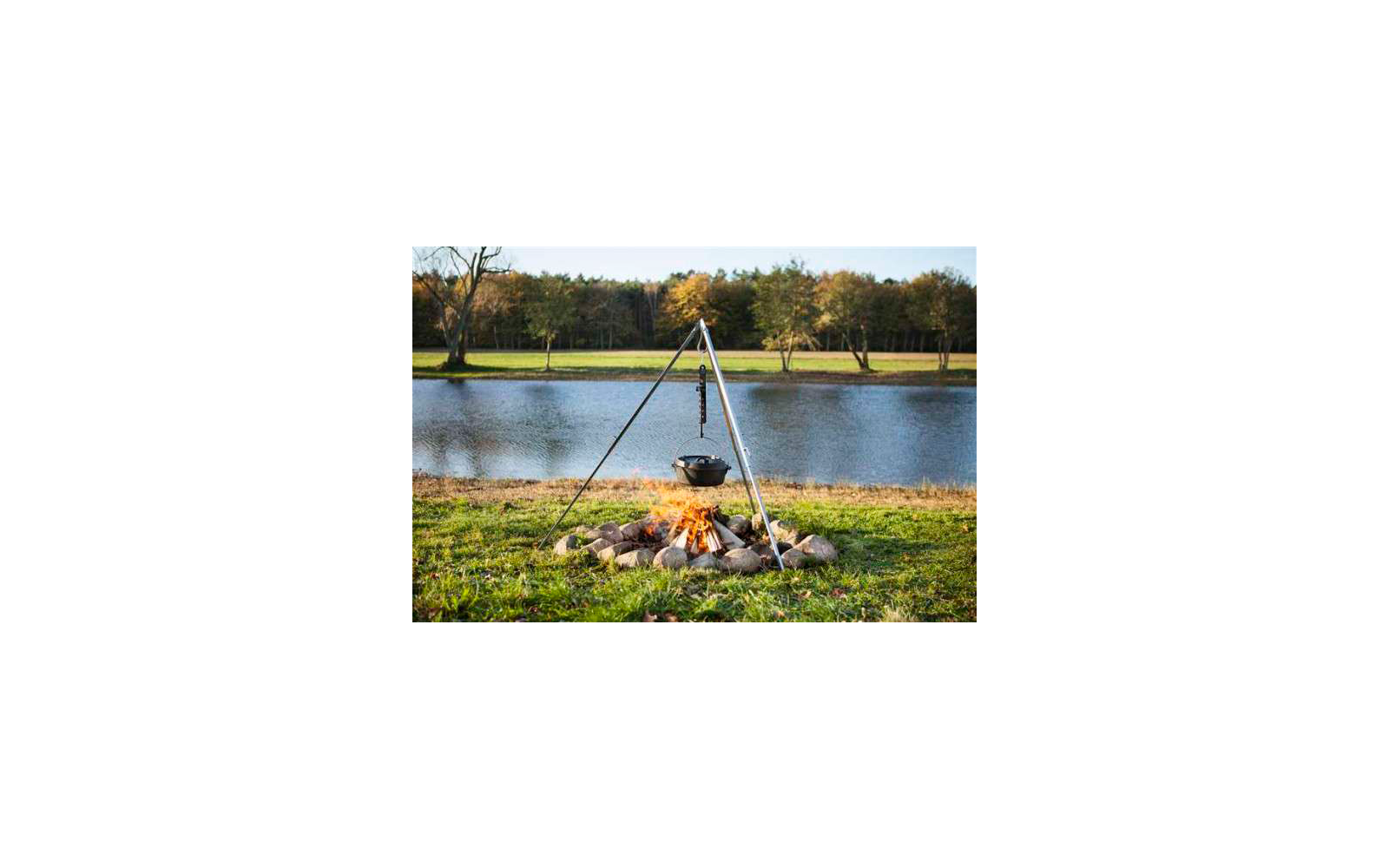 Freiluftfeuerstelle mit kochendem Topf über dem Feuer und See im Hintergrund