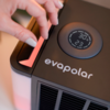 Hand stellt an einem elektronischen Gerät mit Display auf einem Tisch ein
