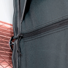 Black zipper on dark fabric next to red and white wall tiles