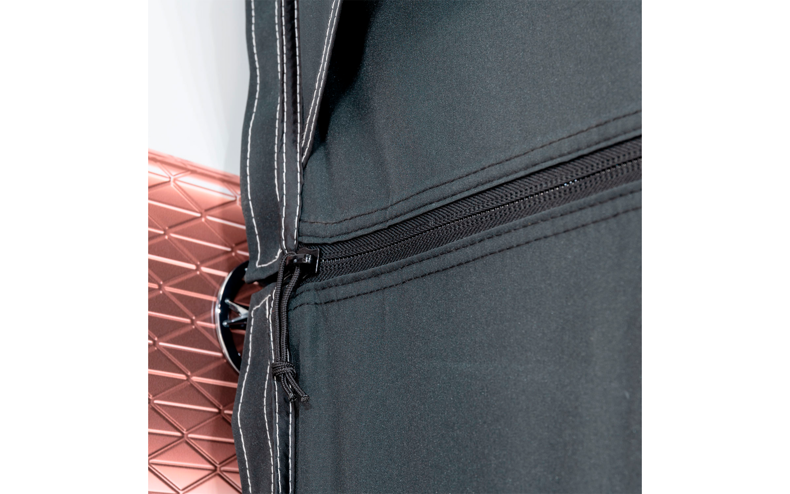 Black zipper on dark fabric next to red and white wall tiles