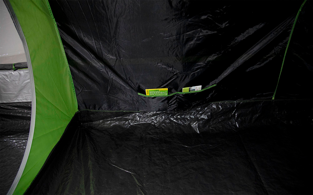 Binnenaanzicht van een tent met zwarte vloer en groene naden