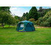 Tenda blu su un prato verde con alberi sullo sfondo