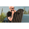 Un hombre con gafas de sol está inflando un colchón inflable negro