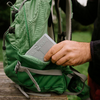 Hand placing a book into a green backpack