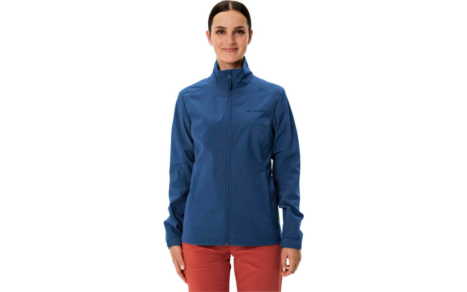 Femme portant une veste bleue et un pantalon rouge, debout devant un fond blanc