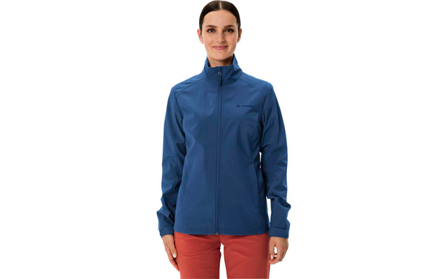 Femme portant une veste bleue et un pantalon rouge, debout devant un fond blanc