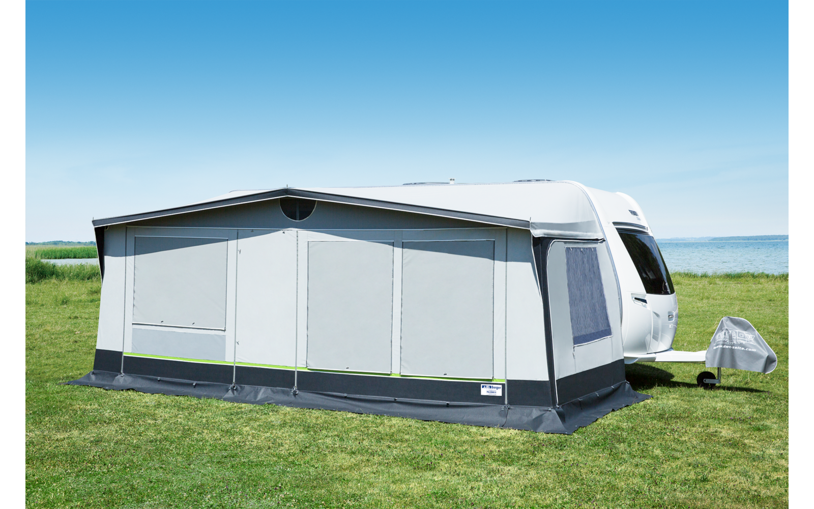 Ein Wohnwagen mit einer geschlossenen weißen Vorzeltplane auf einer Wiese