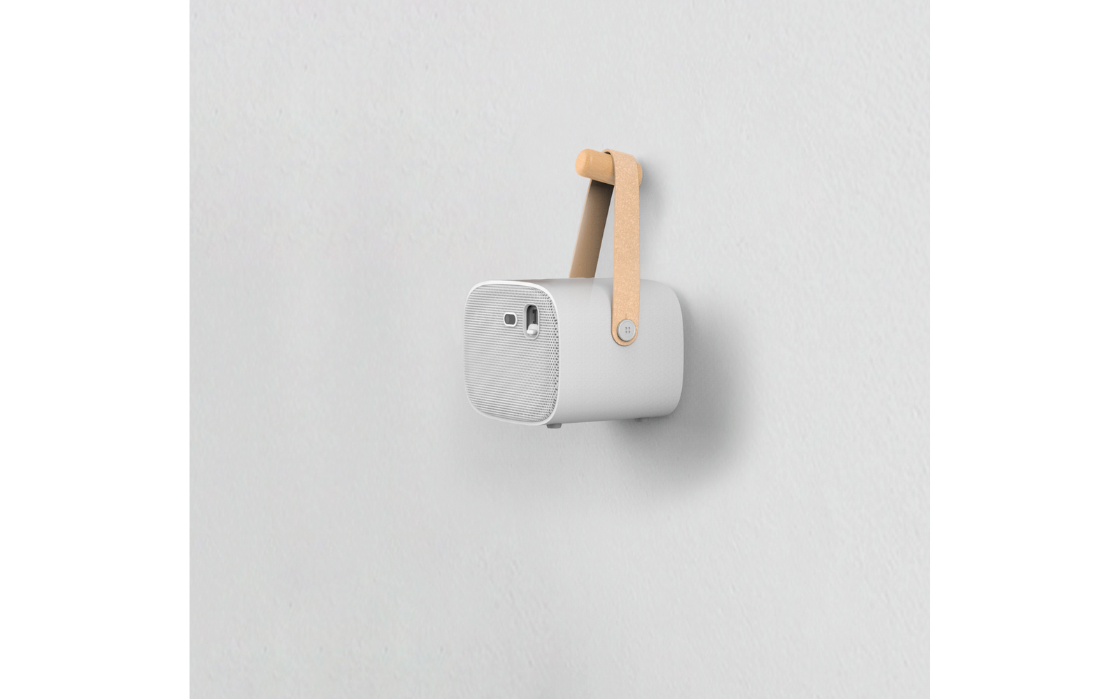 weiße tragbare Bluetooth-Box mit braunem Tragegriff, befestigt an weißer Wand