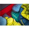 Diverse giacche imbottite colorate sono compresse insieme in un contenitore rosso