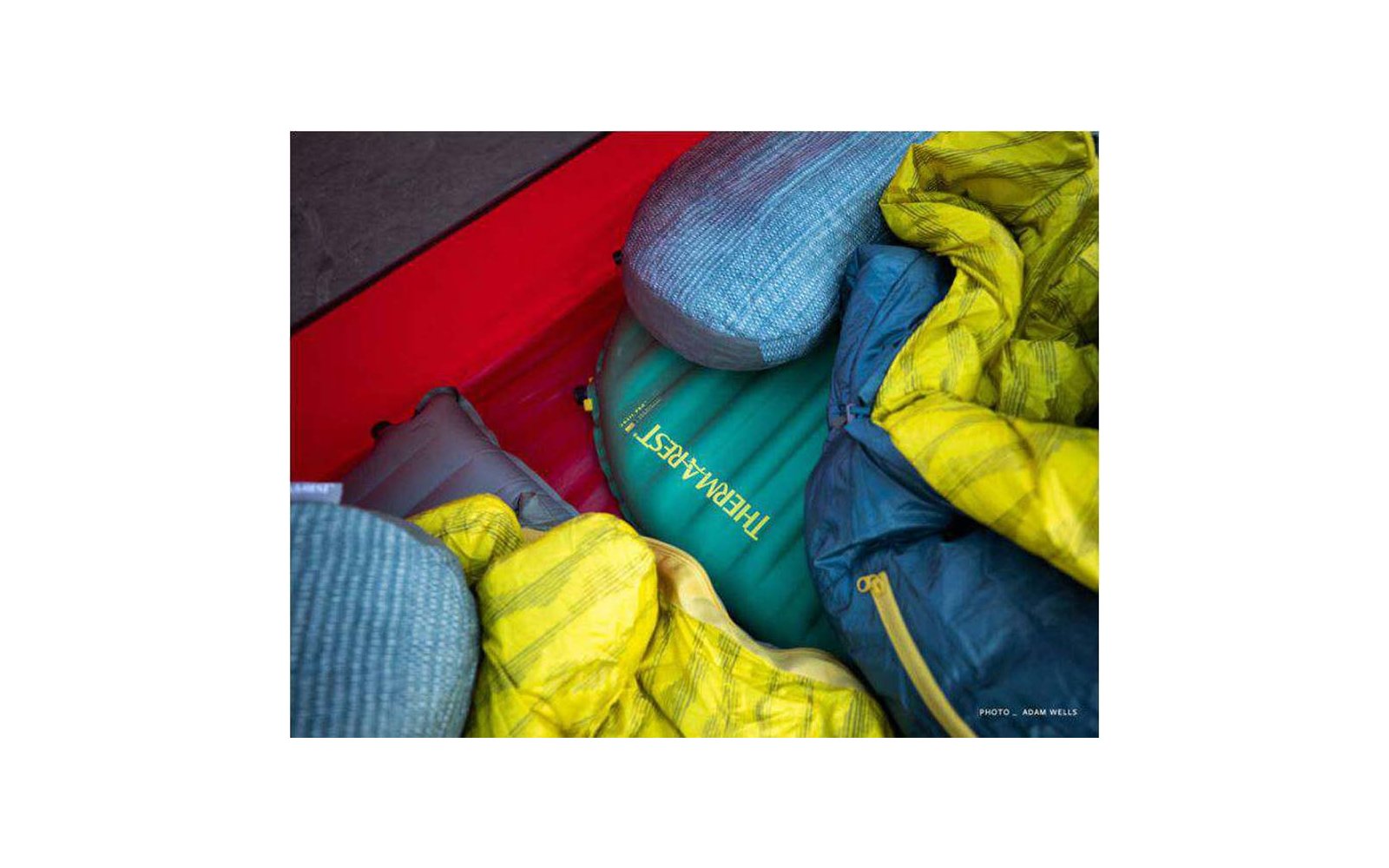 Diverse giacche imbottite colorate sono compresse insieme in un contenitore rosso