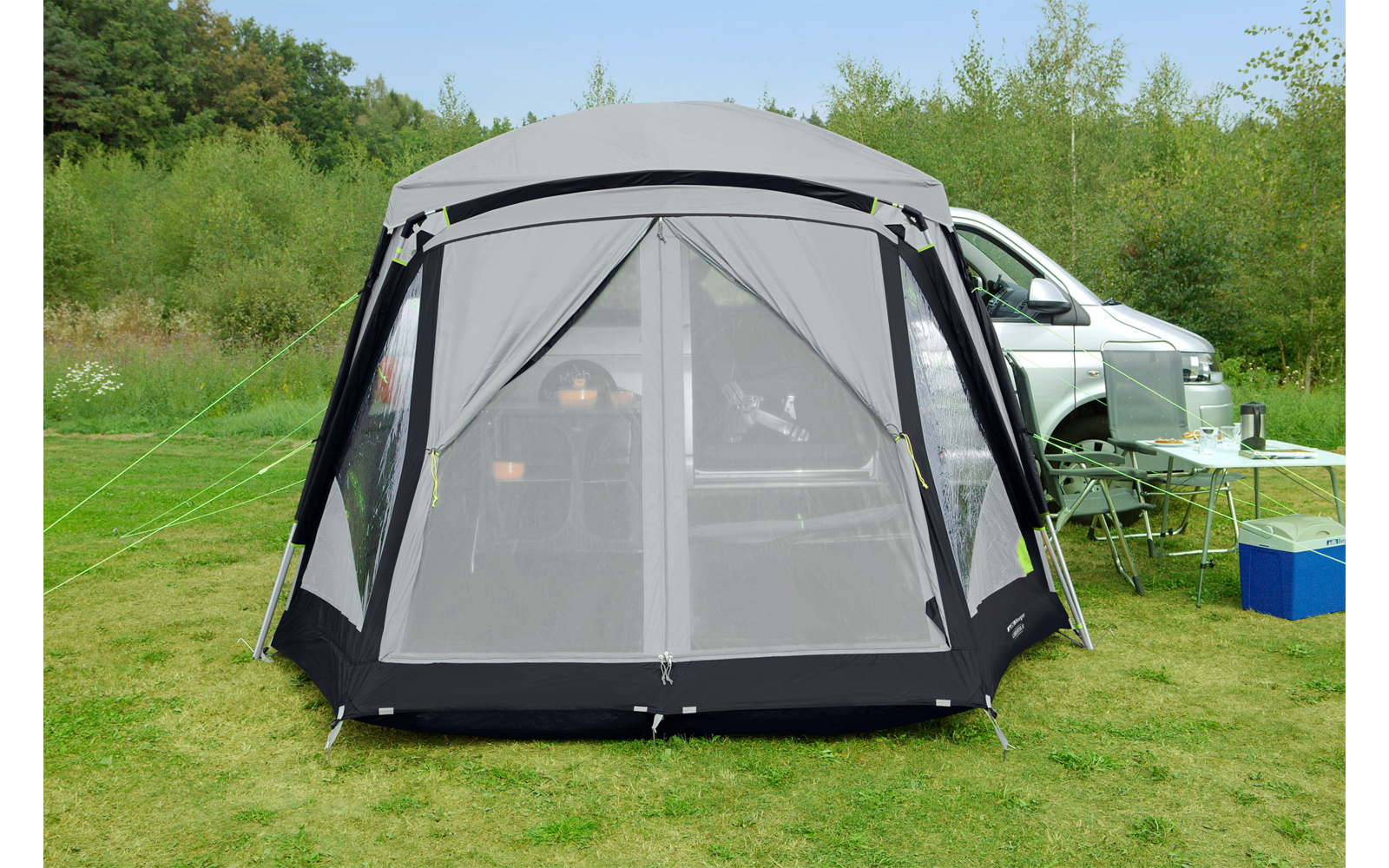 Een meisje zit op het gras voor een kleine grijze tent en kijkt naar rechts