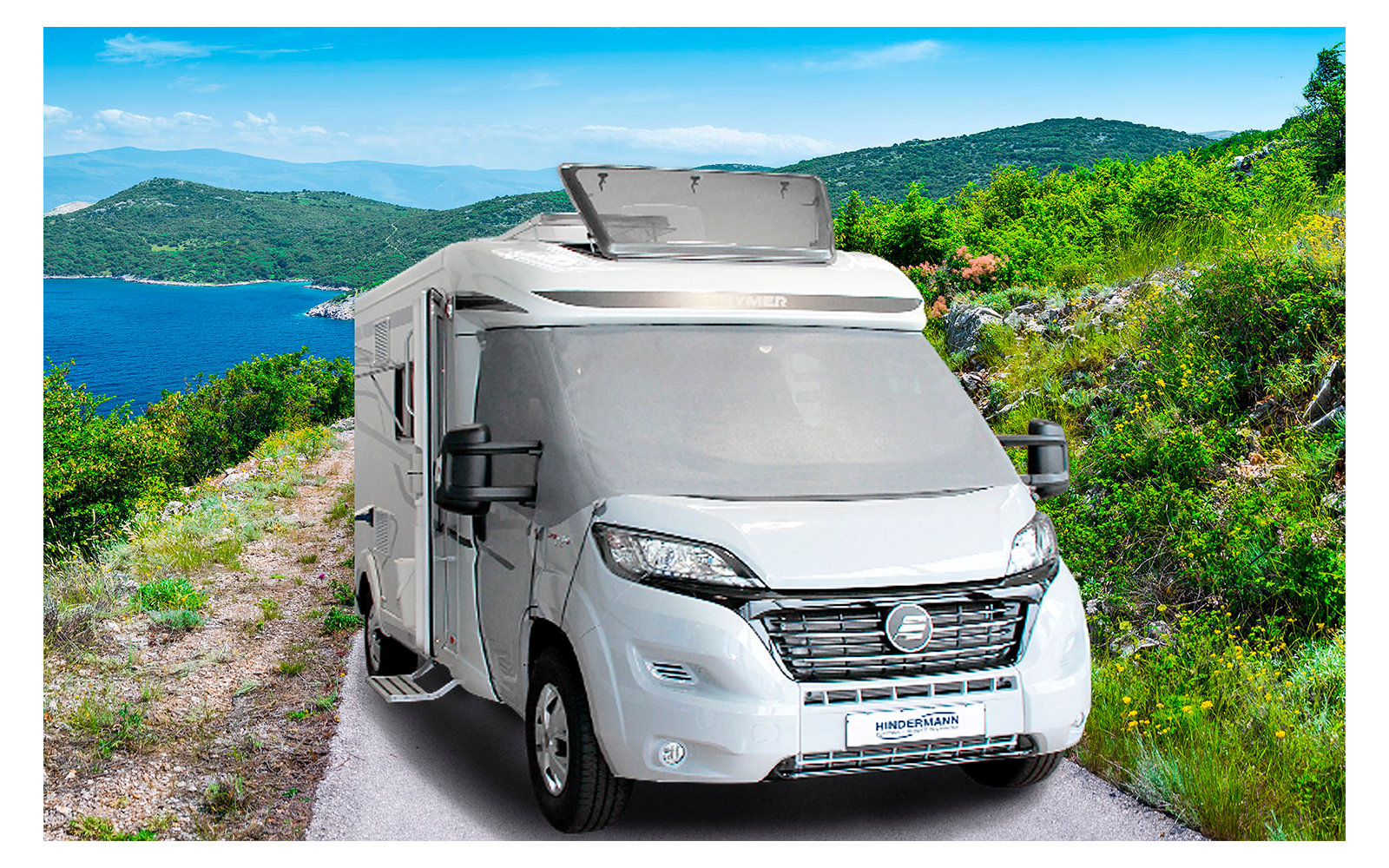 Camping-car sur une route de montagne étroite avec un lac et des collines vertes en arrière-plan