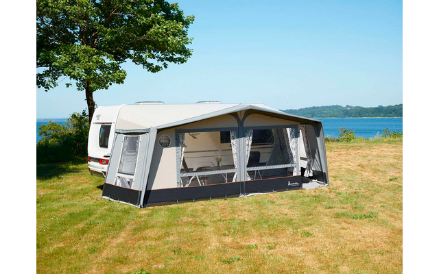 Wohnwagen mit Vorzelt auf einer Wiese neben einem See