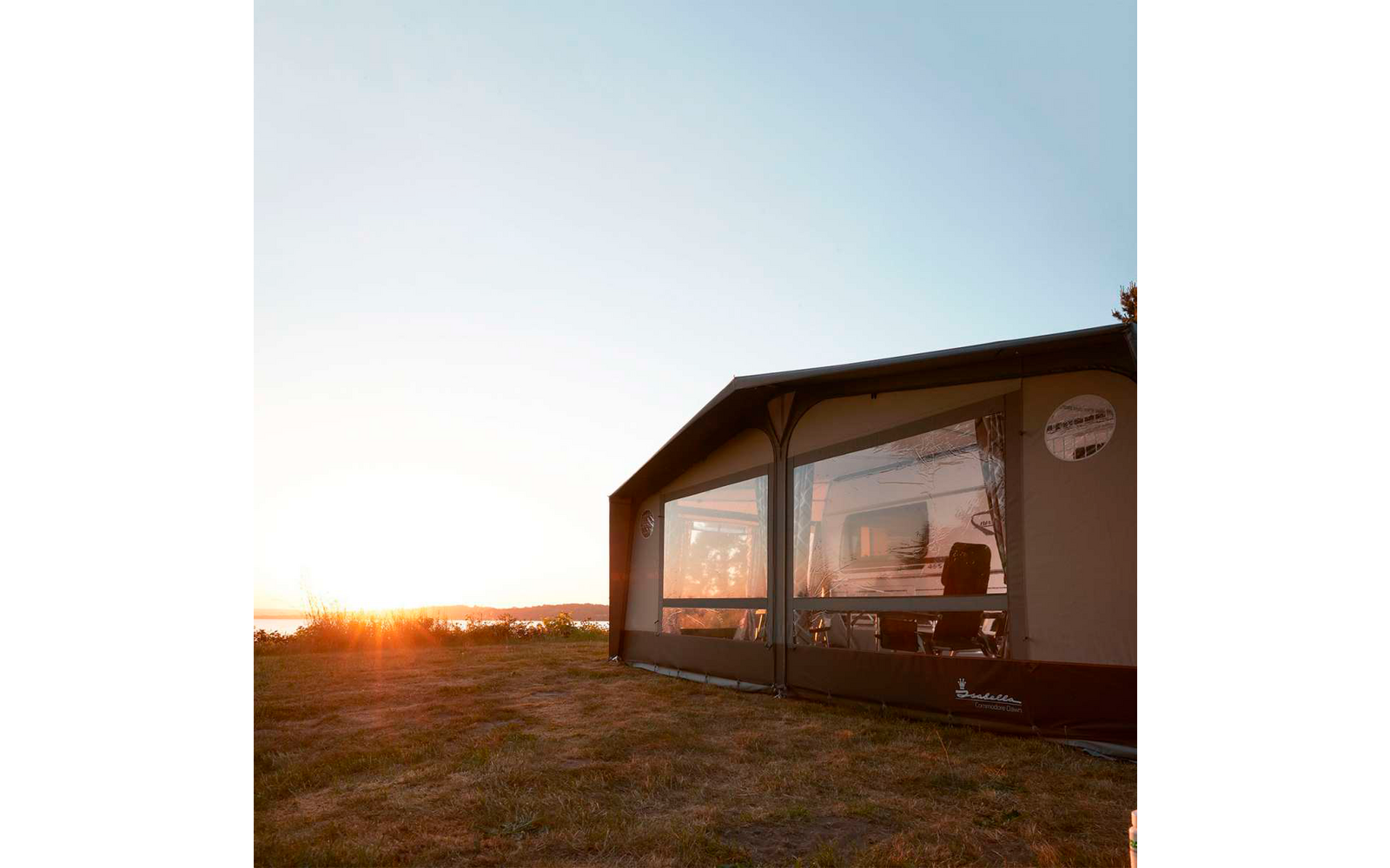 Ein modernes Haus mit großen Fenstern bei Sonnenuntergang auf einem offenen Gelände