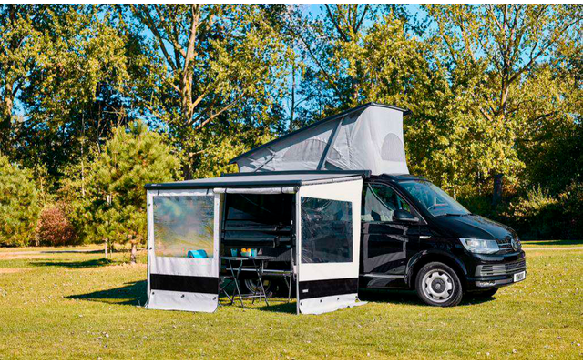 Zwarte bestelwagen geparkeerd voor een gebouw met etalageruiten en een dakterras