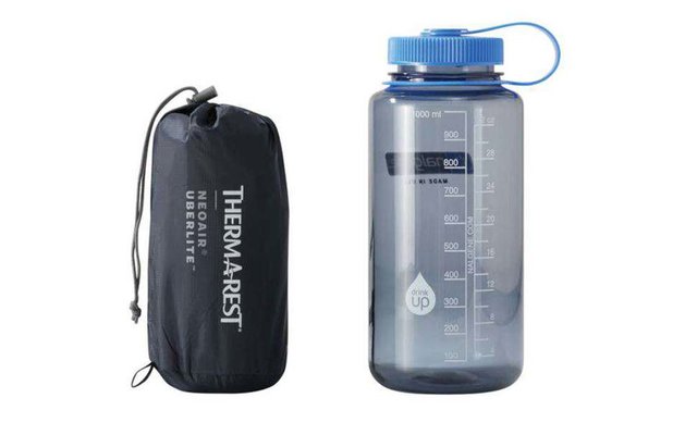 Wasserflasche mit blauen Deckel neben schwarzer Tasche