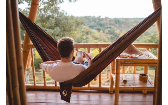 Persona che si rilassa in un'amaca su una terrazza in legno con vista su un paesaggio boscoso
