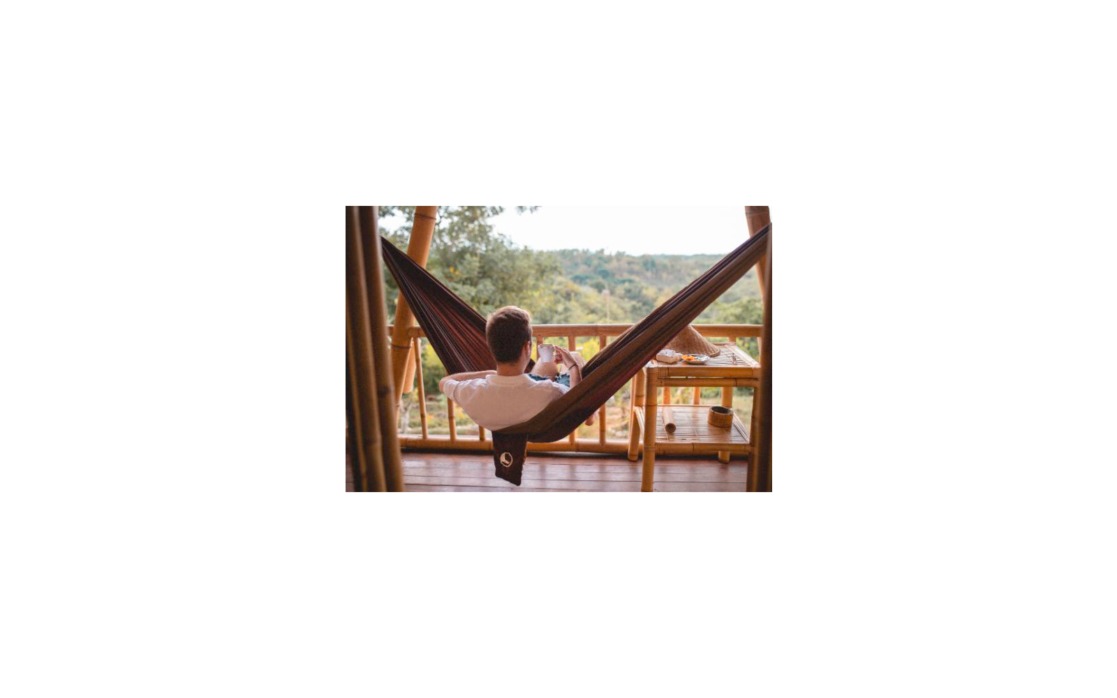 Persona che si rilassa in un'amaca su una terrazza in legno con vista su un paesaggio boscoso