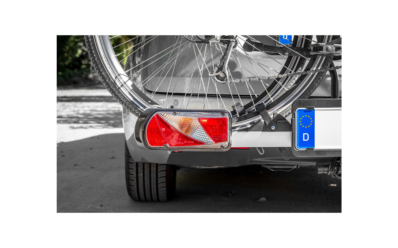 Nahaufnahme des hinteren Teils eines Fahrrads, befestigt an einem Anhänger mit Reflektor und Autokennzeichen
