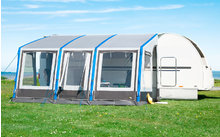 Weißes Wohnmobil mit blauem Vorzelt auf grünem Gras