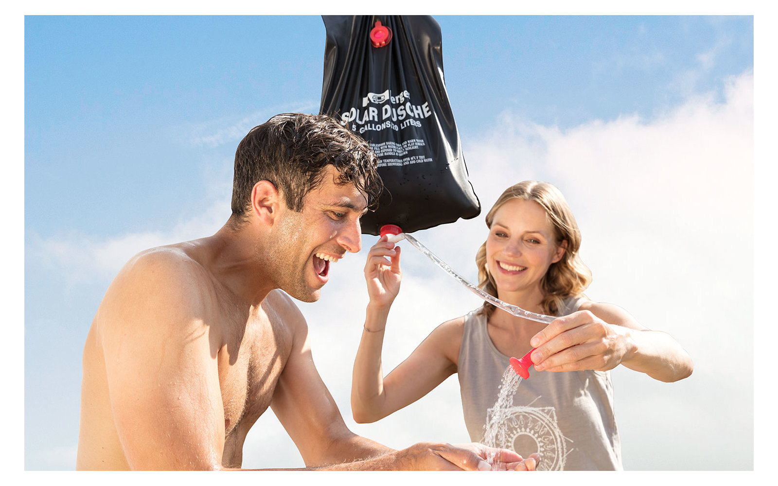 Ein Mann und ein Mädchen im Freien, das Mädchen hält eine Wasserpistole und spritzt Wasser auf den Mann