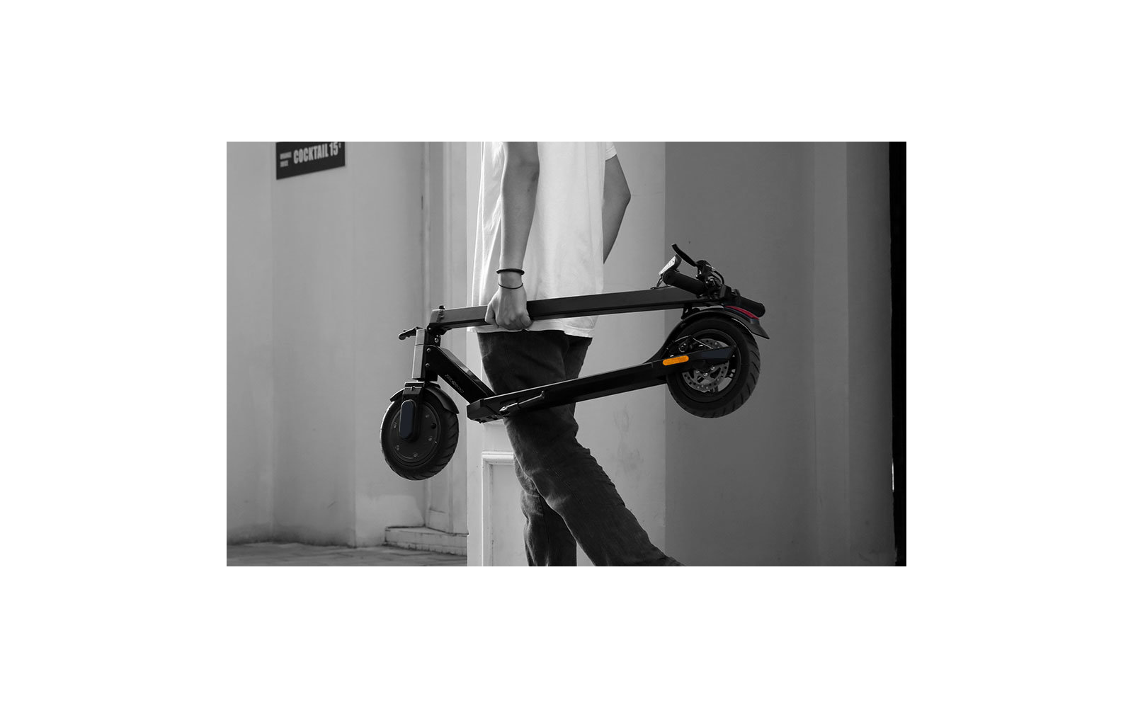 Elektrischer Scooter steht an einem Metallgeländer befestigt vor einer weißen Wand