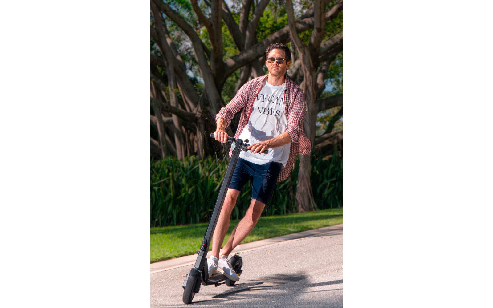 Junge Frau fährt mit E-Scooter auf einem Weg im Freien