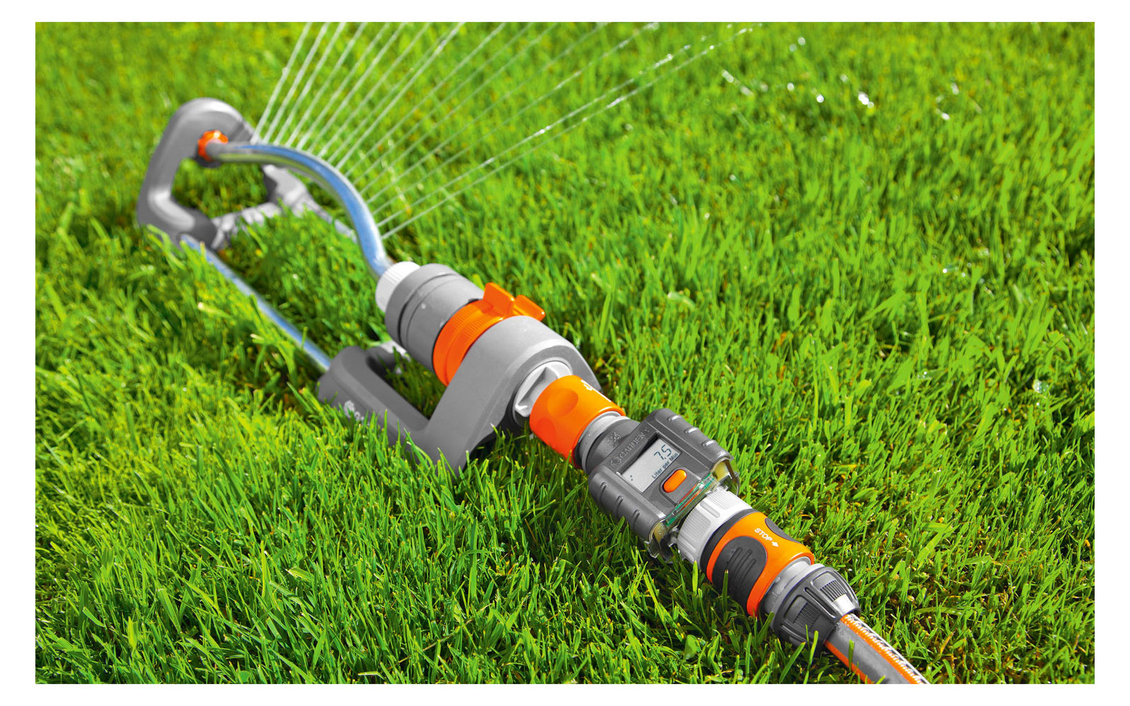 Water hose with spray nozzle on green grass