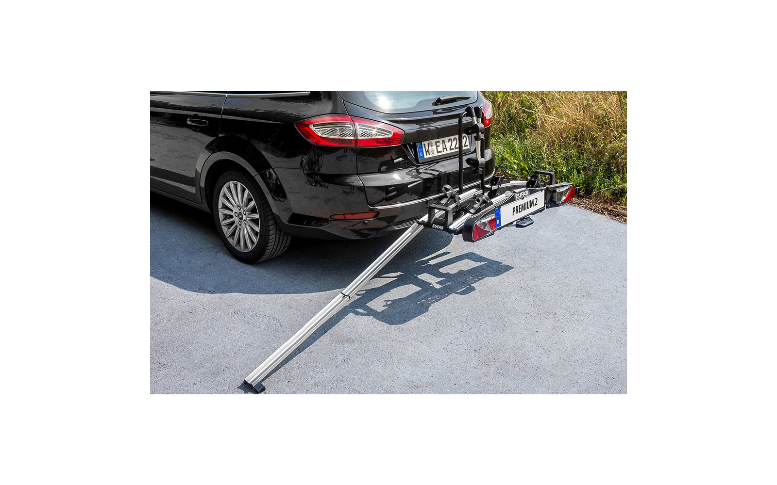 Mehrere Personen in weißer Schutzkleidung und Masken stehen im Grünen und halten ein rotes Banner mit chinesischer Schrift